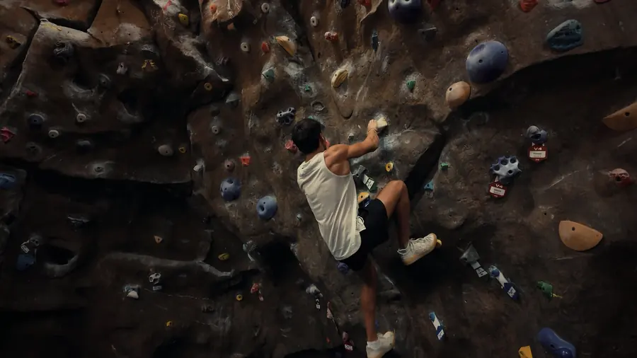 Brennan Harmatz climbing a bouldering wall, seen from above
