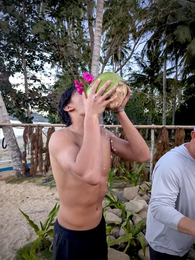 Brennan Harmatz drinking from a coconut on the beach