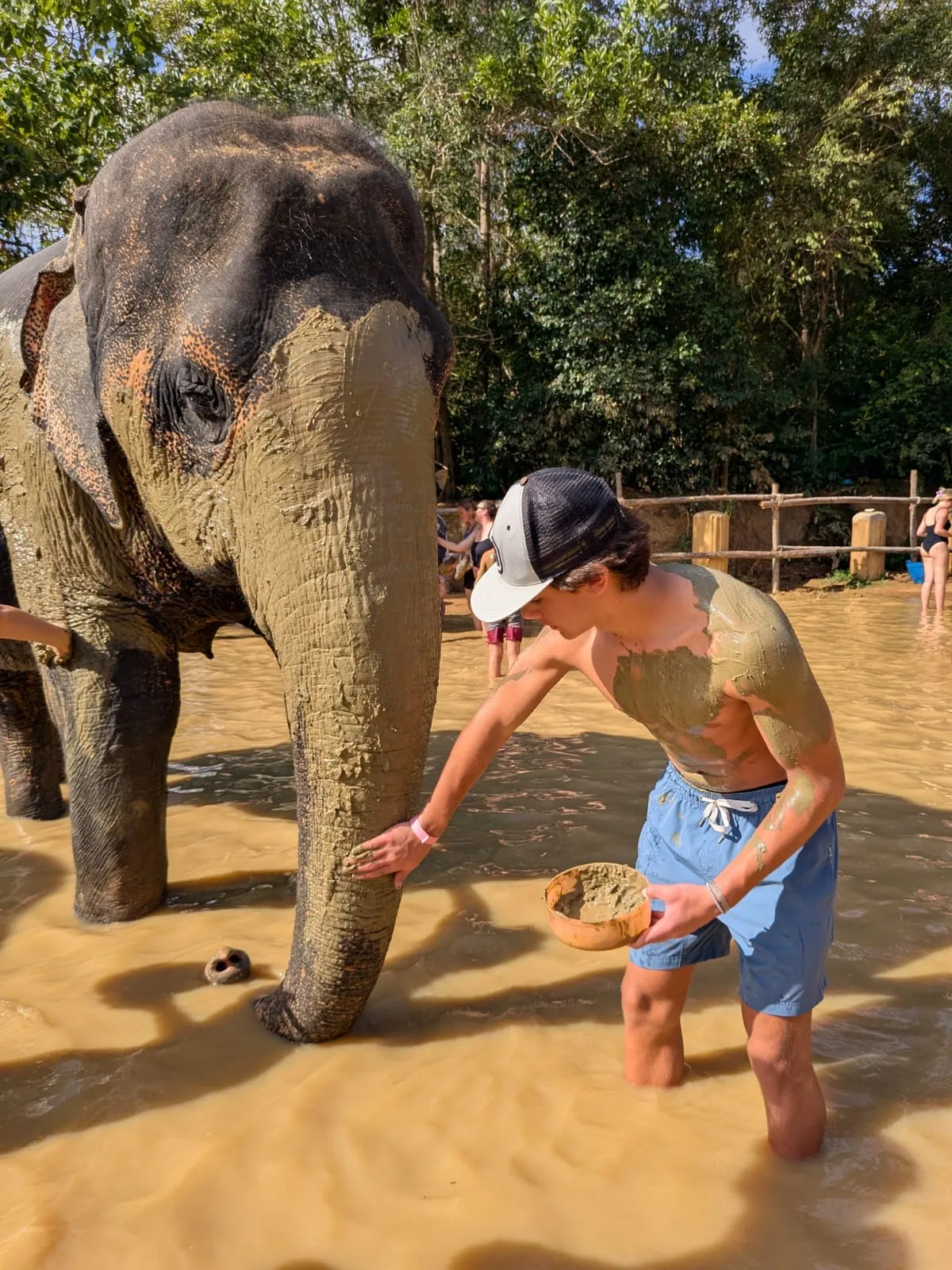 Brennan Harmatz covered in mud beside an elephant