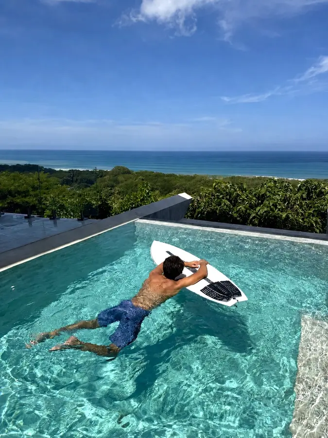 Brennan Harmatz paddling a surfboard in an infinity pool
