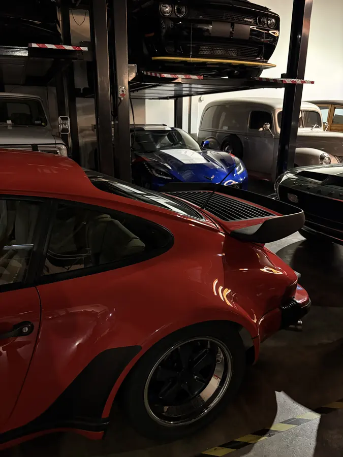 A classic red Porsche in a garage full of cars