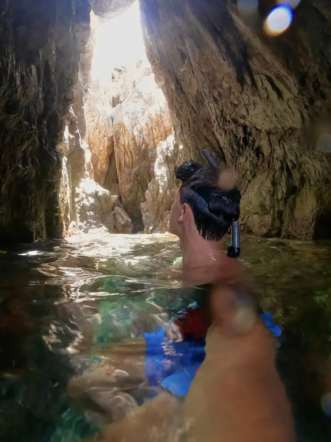 Brennan Harmatz snorkeling in a sea cave lit from above